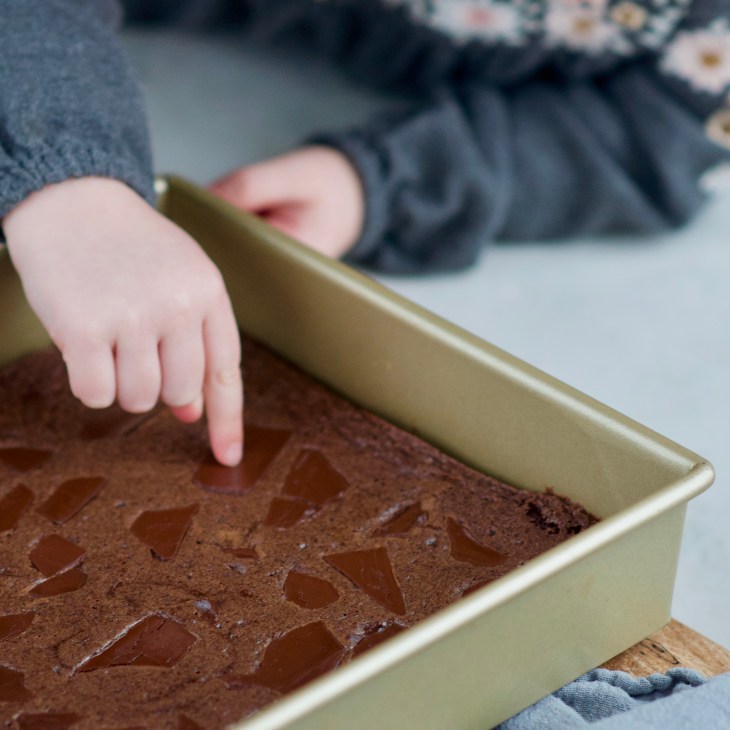 blood orange brownies in a pan, being touched
